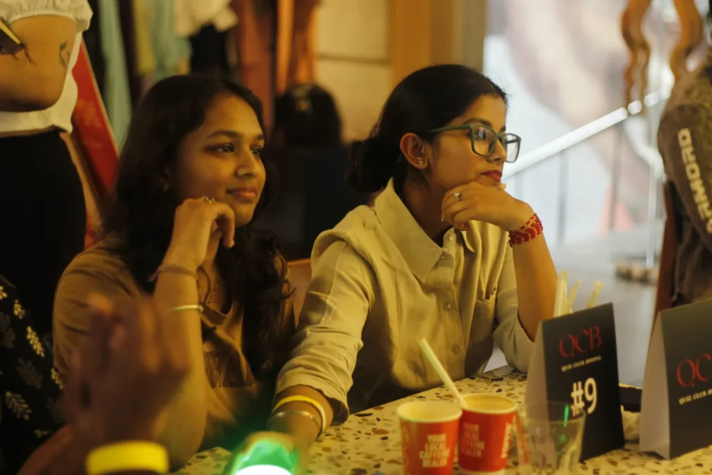 Two participants at their table during a quiz round, buzzer lit up